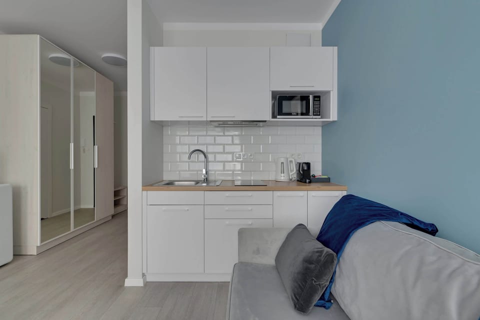 Apartament oferuje funkcjonalny aneks kuchenny z niezbędnym wyposażeniem, stół z krzesłami oraz zestaw powitalny z kawą, herbatą i przyprawami.