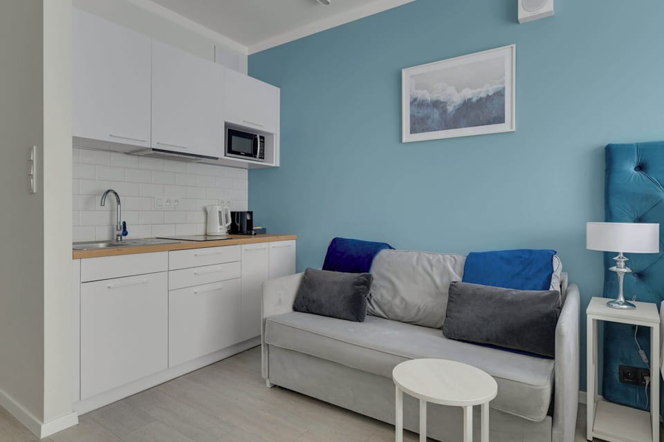 Apartament oferuje funkcjonalny aneks kuchenny z niezbędnym wyposażeniem, stół z krzesłami oraz zestaw powitalny z kawą, herbatą i przyprawami.