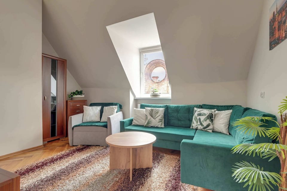 Salon stanowi przytulną strefę wypoczynku, w której znajduje się wygodna, rozkładana sofa pełniąca również funkcję dodatkowego miejsca do spania. Naprzeciwko umieszczono telewizor z dostępem do kanałów kablowych oraz funkcją Smart TV.