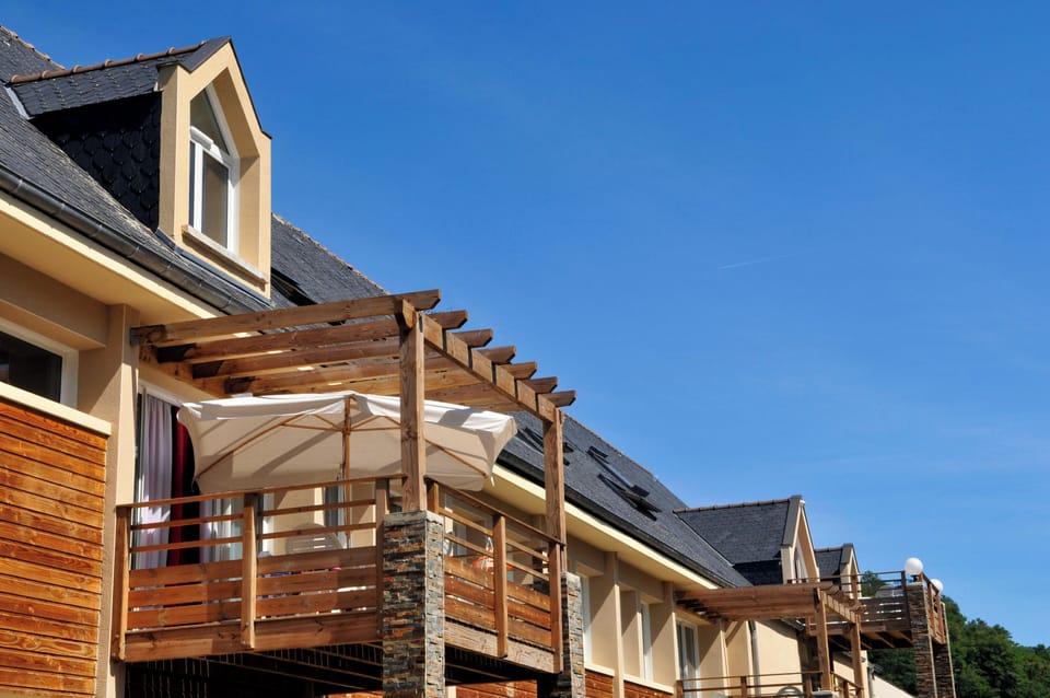 The residence building nestled into the hillside above the Lot valley, surrounded by the lush green landscape of the Aveyron.