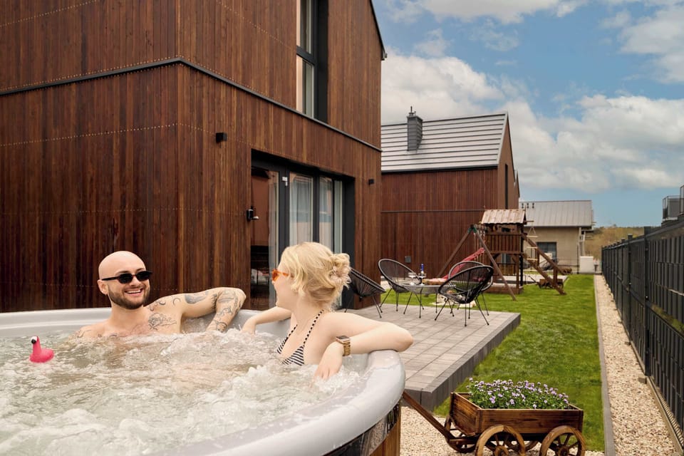 Za domkiem znajduje się przestronny, prywatny taras wyposażony w wygodne fotele ogrodowe oraz stolik. Dodatkowym atutem jest znajdujące się na tarasie prywatne jacuzzi.