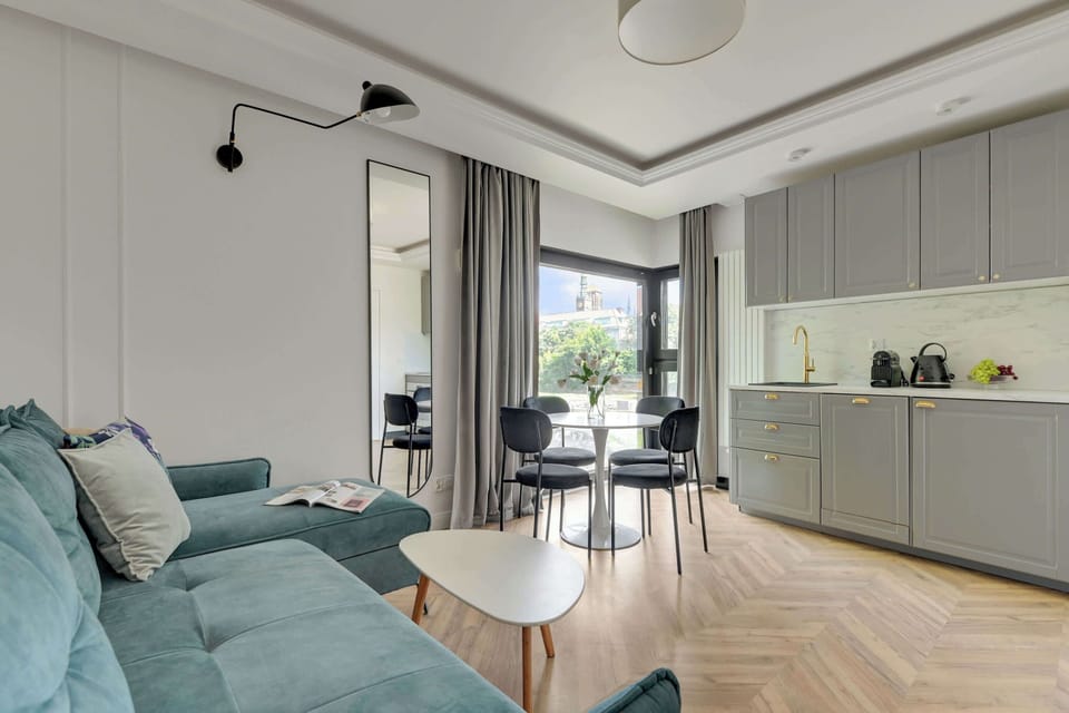 Głównym pomieszczeniem apartamentu jest przestronny salon, który pełni funkcję zarówno strefy wypoczynkowej, jak i jadalnianej. Znajduje się w nim wygodna rozkładana sofa, zapewniająca dodatkowe miejsce do spania. 