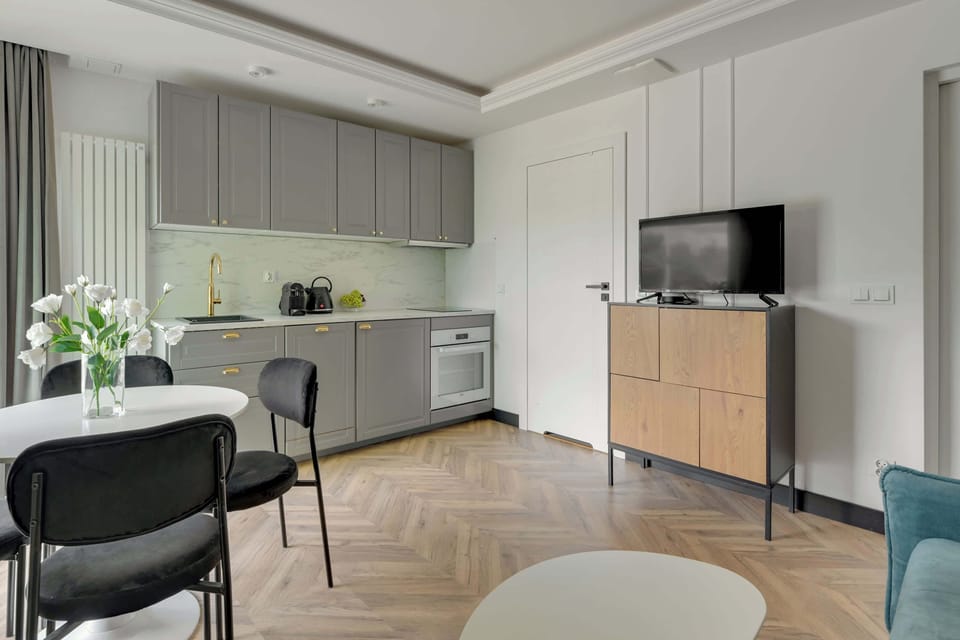 Głównym pomieszczeniem apartamentu jest przestronny salon, który pełni funkcję zarówno strefy wypoczynkowej, jak i jadalnianej. Znajduje się w nim wygodna rozkładana sofa, zapewniająca dodatkowe miejsce do spania. 