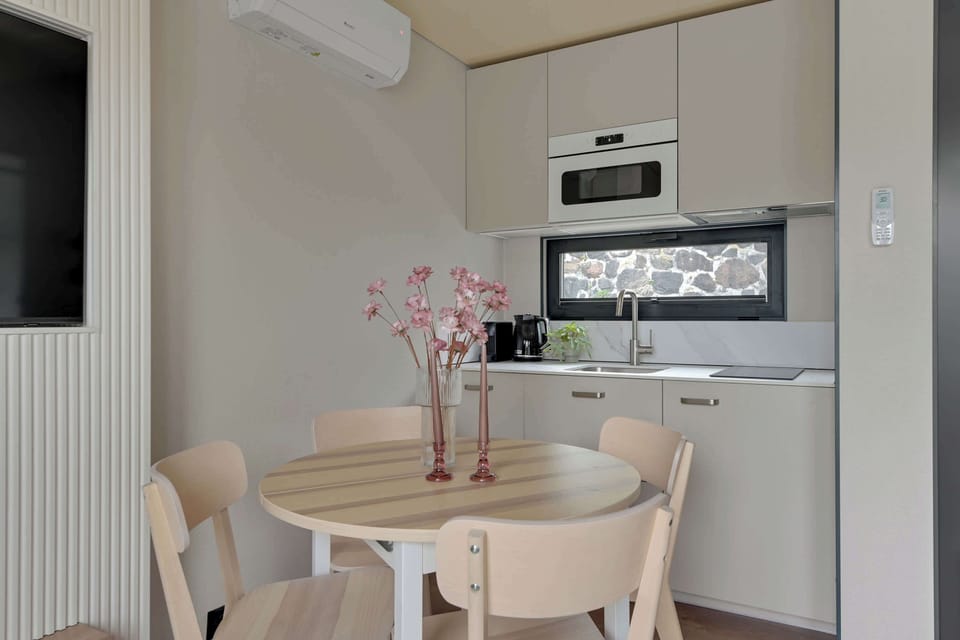 W sercu domku znajduje się funkcjonalny aneks kuchenny, który łączy estetykę z wygodą. Jasne fronty szafek, nowoczesne wyposażenie i minimalistyczny design sprawiają, że gotowanie nawet prostych posiłków staje się przyjemnością. 