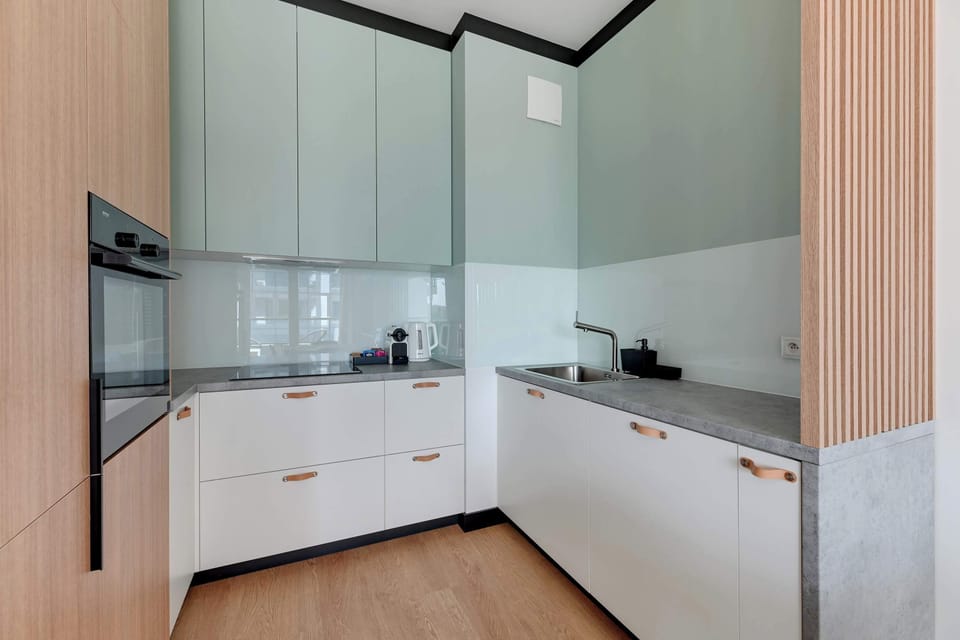 Apartament posiada w pełni wyposażony aneks kuchenny, w którym znajdują się piekarnik, kuchenka mikrofalowa, zmywarka, płyta indukcyjna oraz niezbędne akcesoria do przygotowywania posiłków. 