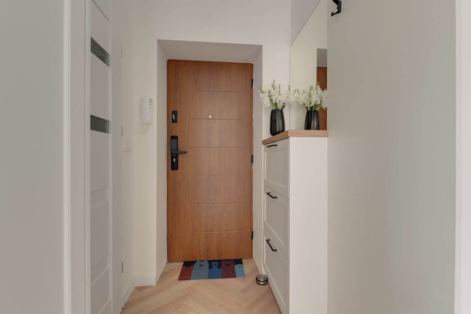 Główną część apartamentu stanowi wygodne łóżko małżeńskie przygotowane dla dwóch osób. Granatowa narzuta, miękkie poduszki oraz starannie ułożone ręczniki tworzą przyjemne, hotelowe wrażenie.