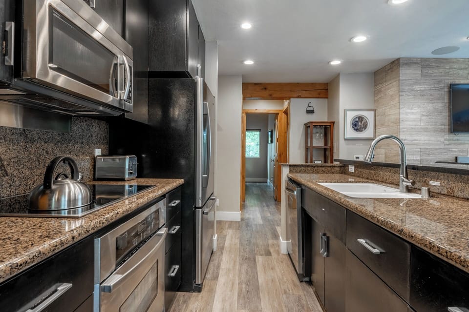 Your fully equipped kitchen features stainless steel appliances, granite counters, and ample space for preparing meals together during your mountain getaway.