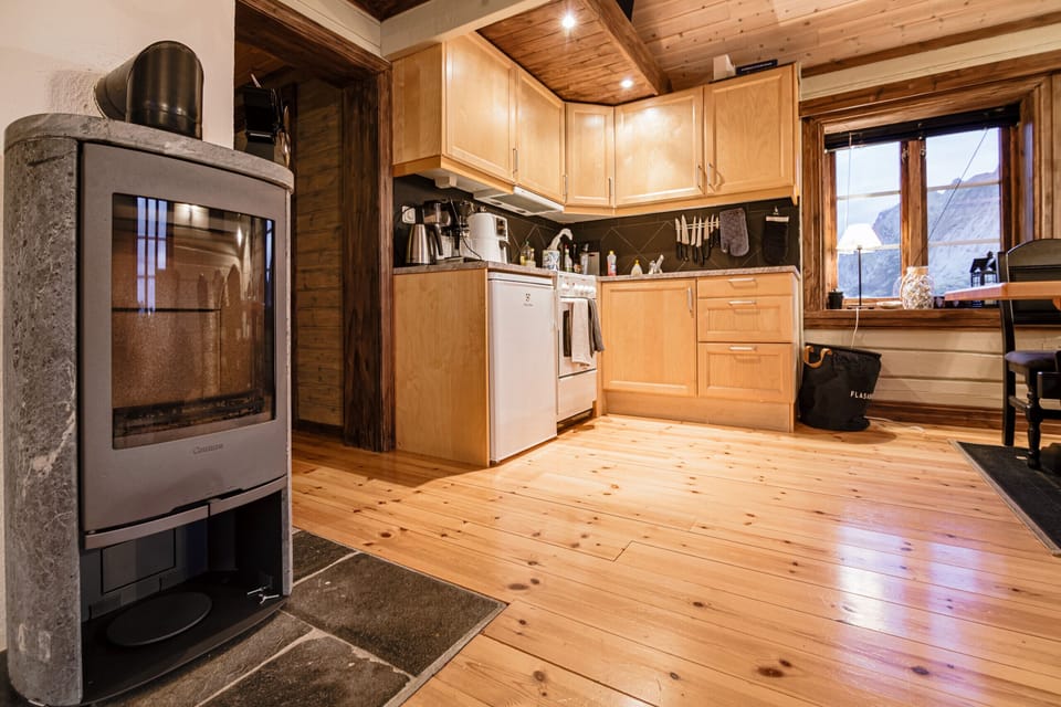 Modest kitchen with a smaller fridge, stove, coffee maker and waterboiler.