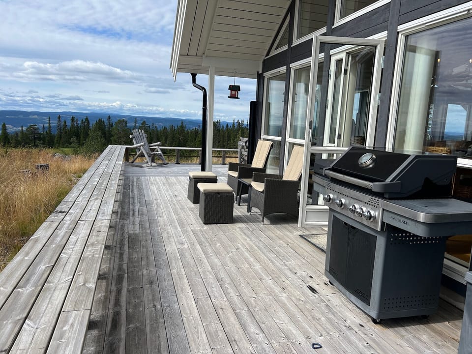 Large terrace with outdoor furniture, a fireplace and a grill