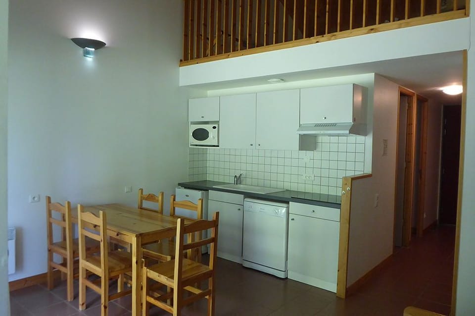 Kitchenette with vitroceramic hob, dishwasher, microwave, and fridge — everything for a self-catered stay.