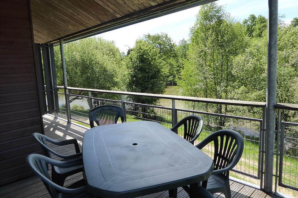 Terrace with a table and chairs looking out over the treetops and the lake.