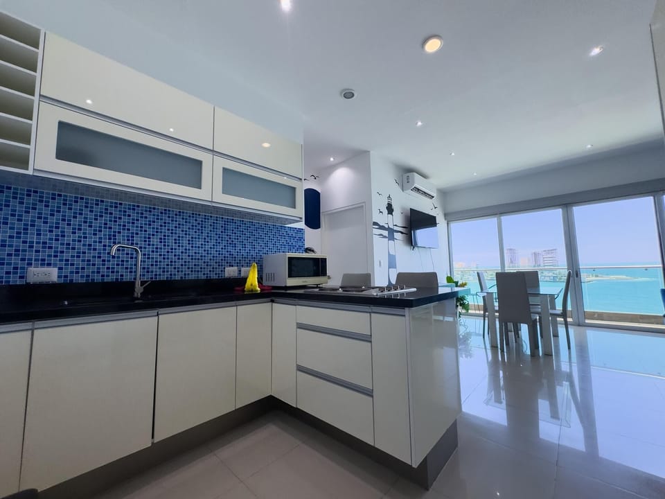 Glossy white cabinets and a blue mosaic tile backsplash surround the black granite kitchen counters.