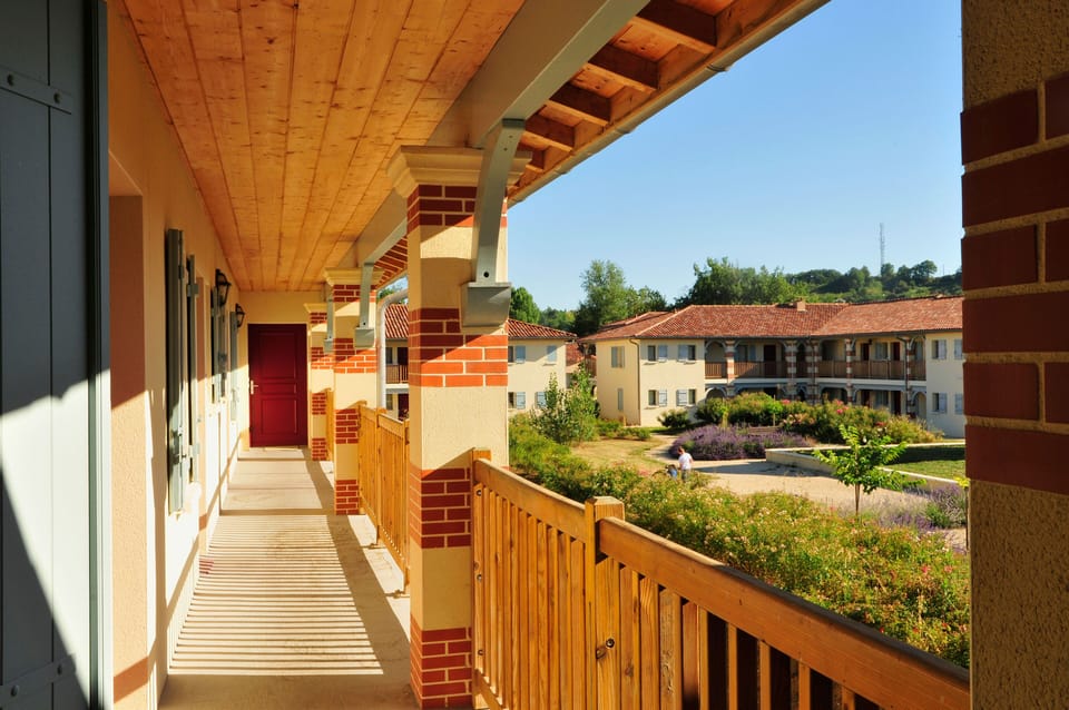 The upper-floor gallery runs along the building front, overlooking the landscaped gardens and children's play area.