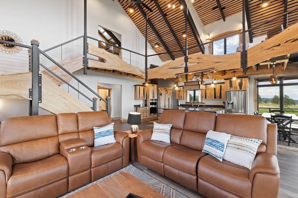This open-concept space showcases warm wood accents throughout the cozy living area, fully equipped kitchen, dining space, and spacious upper loft, creating a welcoming mountain retreat.