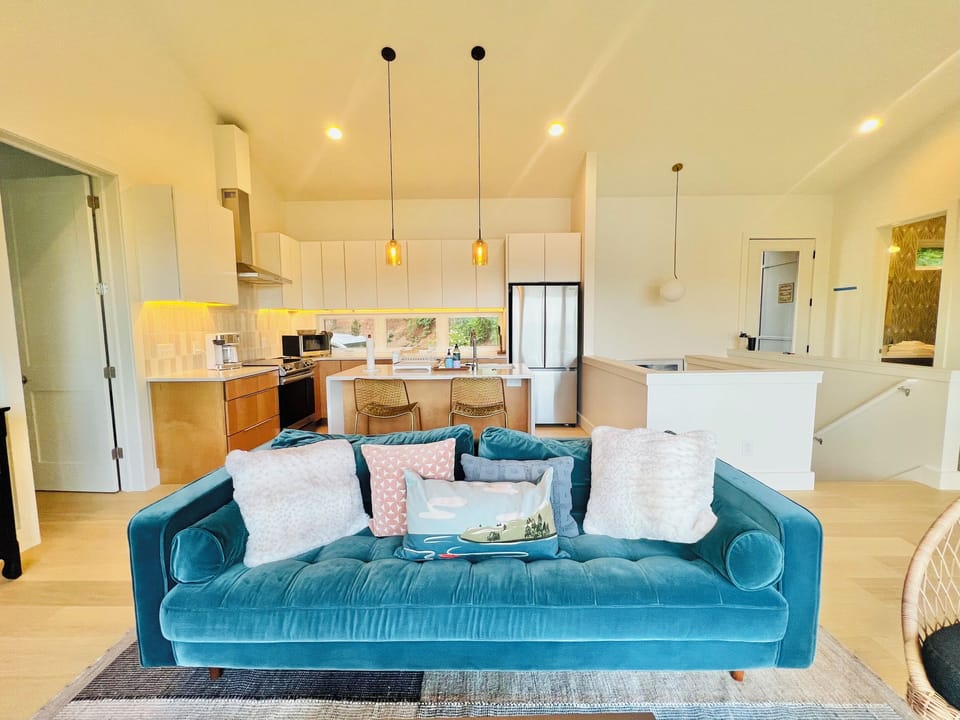 Relax and unwind. The main-level living room offers comfortable seating, a Smart TV, a wood-burning stove, and direct access to the covered deck. Large windows and glass doors keep the lake and mountain views front and center.