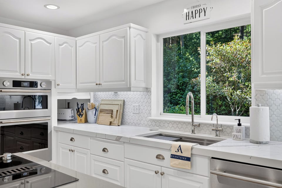 Kitchen sink area featuring view-framing windows that overlook the lush, surrounding forest.