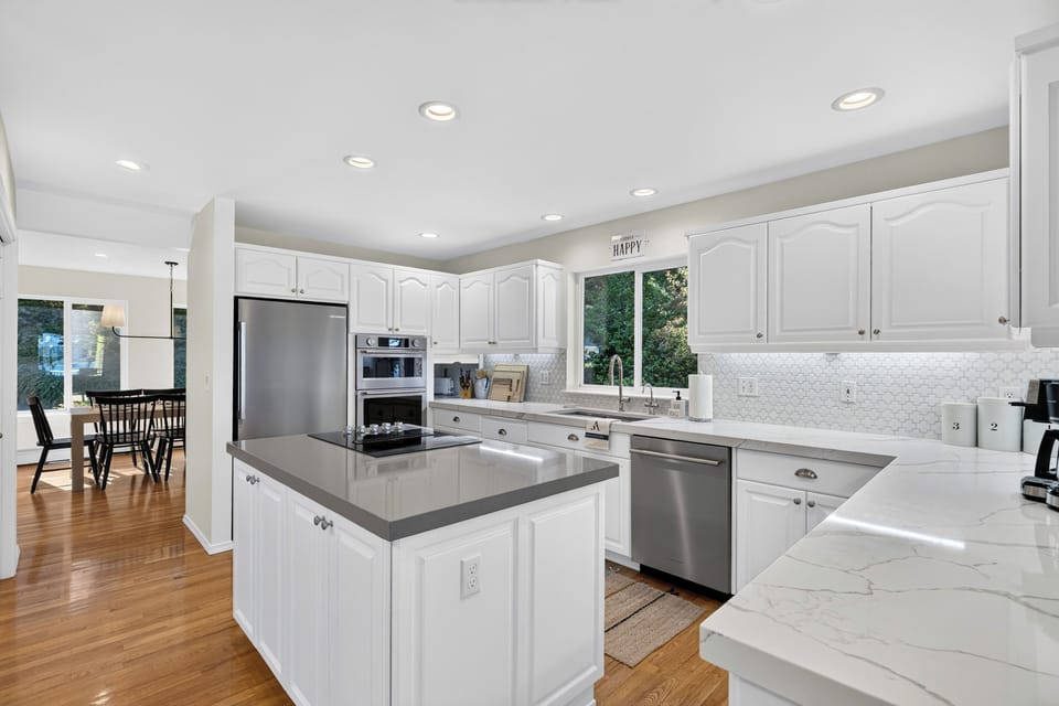 High-end stainless steel appliances complement the bright white kitchen and solid-surface countertops.
