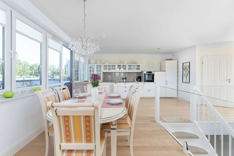 Sunny dining area with a large dining table, floor-to-ceiling windows, and direct access to the balcony.