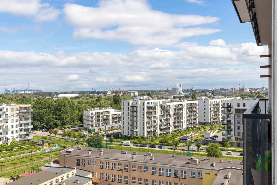 Another angle from the high-floor balcony captures the rooftops and courtyards of the contemporary neighborhood. Lush green spaces contrast beautifully with the clean architecture of the housing development.