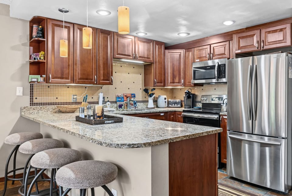 Your fully equipped chef's kitchen features granite countertops, rich wood cabinetry, and stainless steel appliances—perfect for preparing memorable meals at the breakfast bar with cozy seating.
