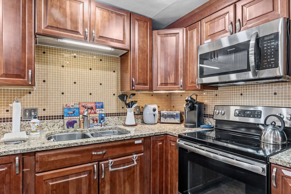 Your fully equipped kitchen features modern stainless steel appliances, warm wood cabinetry, and granite countertops, perfect for whipping up meals during your stay.