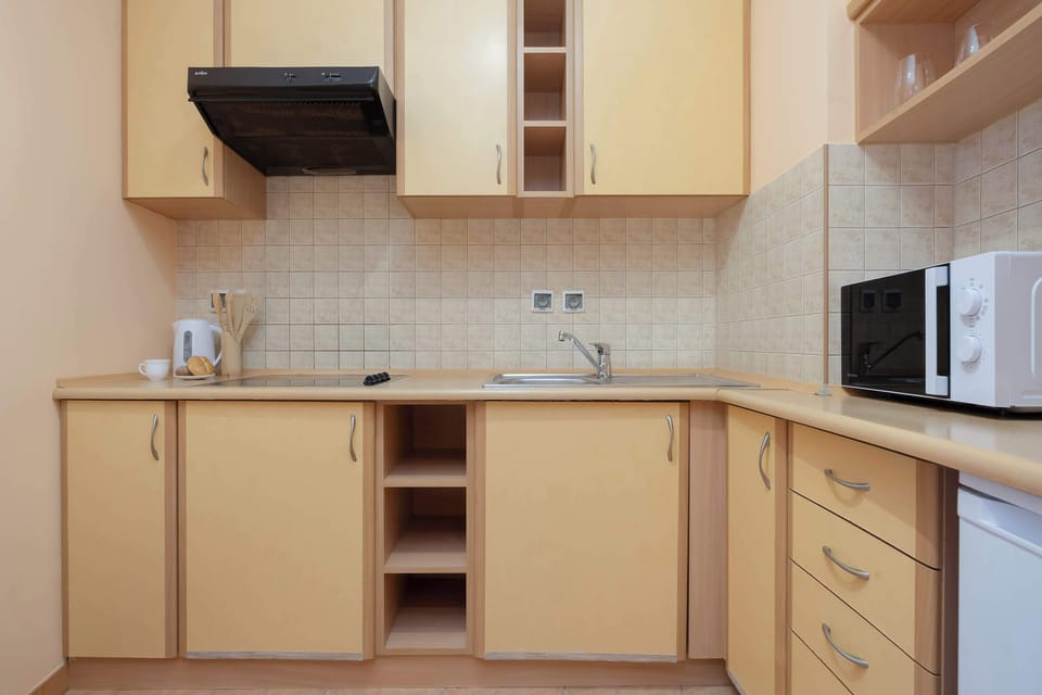 An L-shaped kitchen offers generous countertop space, wooden cabinetry, and essential appliances. Open shelves provide additional storage for kitchen items.
