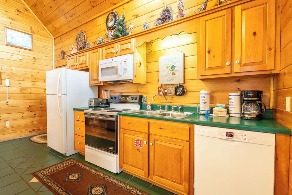 Your fully-equipped kitchen features warm wood cabinetry, modern appliances, and a welcoming green countertop—perfect for preparing cozy meals during your mountain getaway.