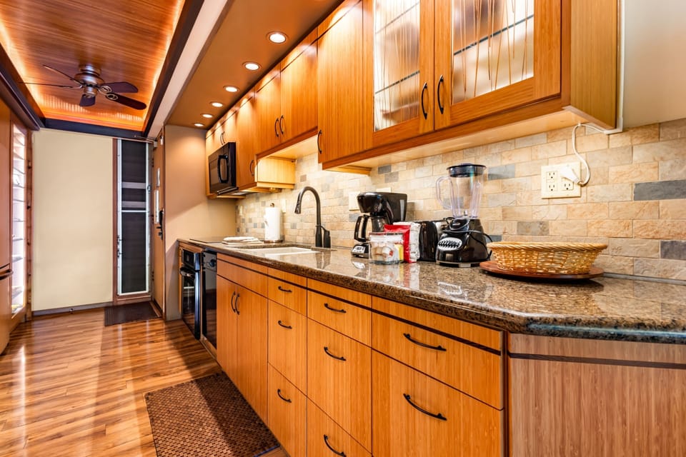 You'll love cooking in this beautifully appointed kitchen, featuring warm wood cabinetry, granite countertops, and a full suite of appliances including a coffee maker and blender for your morning routine.