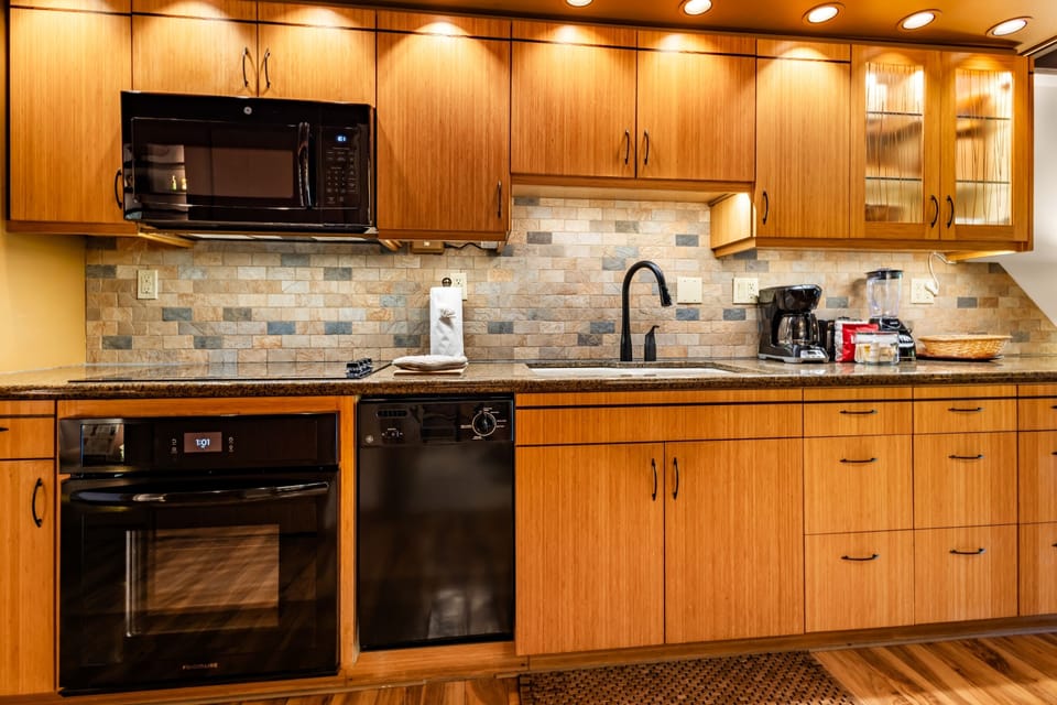 Your spacious kitchen features gleaming granite counters, rich wood cabinetry, and everything you need to prepare meals—microwave, oven, dishwasher, and coffee maker all within reach.