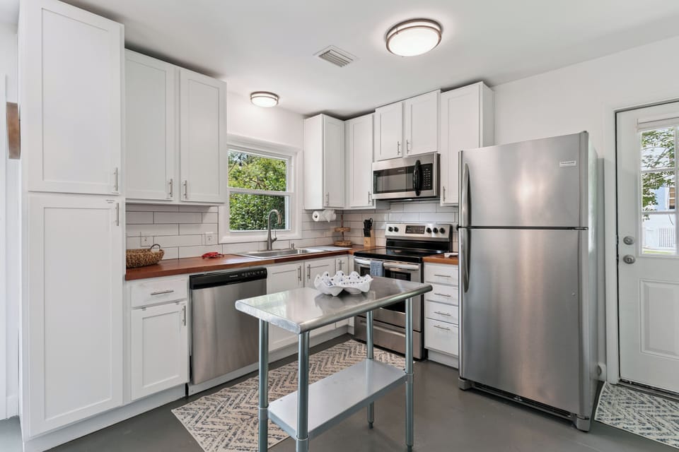 Step into your bright, fully equipped kitchen with stainless steel appliances, warm wood countertops, and crisp white cabinetry—perfect for whipping up meals or morning coffee.