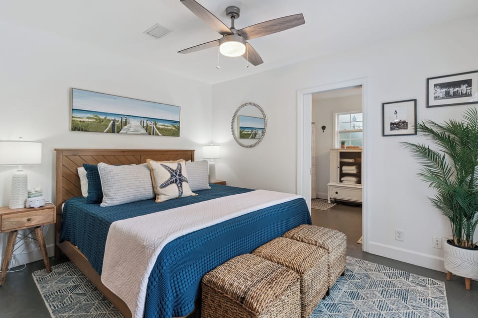 Settle into this coastal-themed bedroom where you'll find restful nights beneath a gentle ceiling fan. The coastal decor and glimpses of nearby spaces invite you to relax and recharge.
