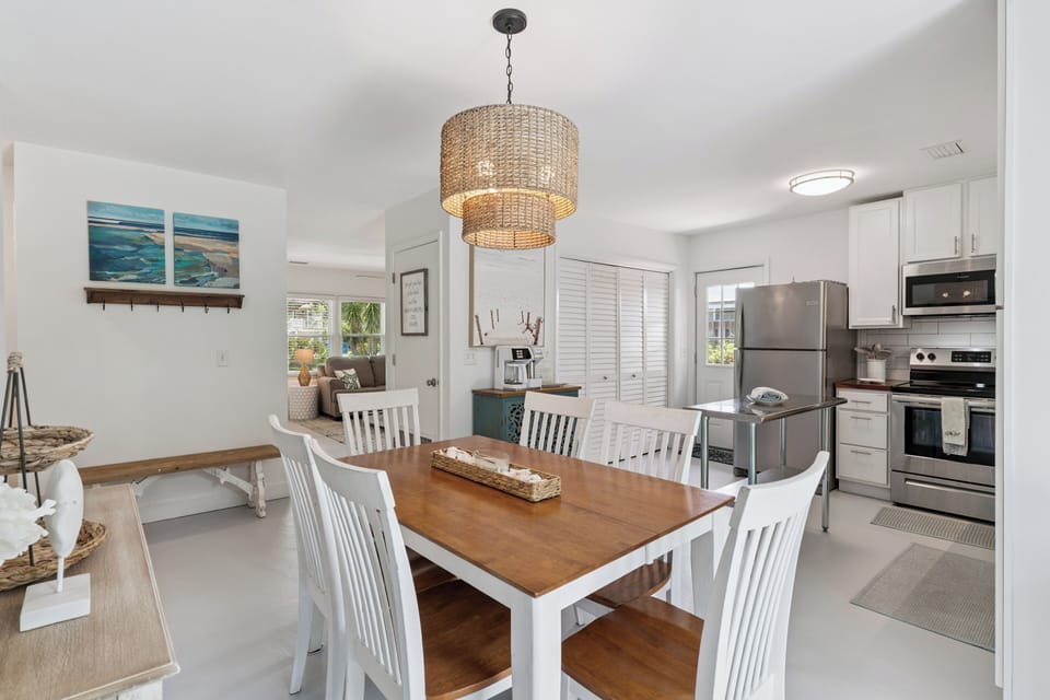 Your inviting dining area flows seamlessly into a fully equipped kitchen, perfect for gathering with loved ones over home-cooked meals under warm coastal-inspired lighting.