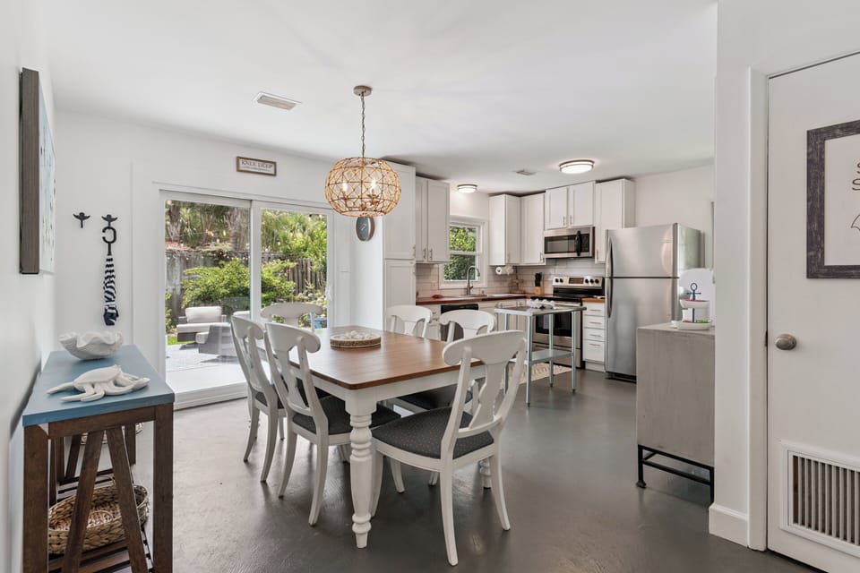 Gather around your farmhouse-style dining table where the warm wood tones invite leisurely meals. Sunlight streams through sliding glass doors, connecting you to the peaceful backyard oasis just steps away.