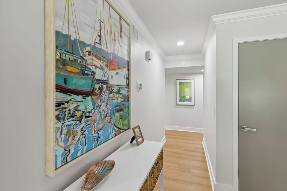 Bright hallway welcoming you with coastal-inspired artwork and warm wood flooring that flows throughout your space.