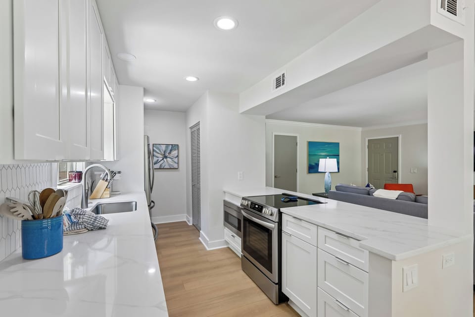 Bright, modern kitchen with sleek white cabinetry and glossy countertops that open seamlessly into the living area—ideal for entertaining while you cook.