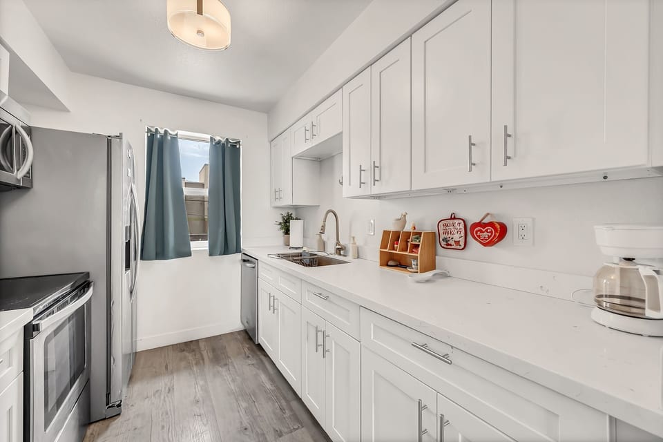 Modern kitchen featuring stainless steel appliances and bright white cabinetry.