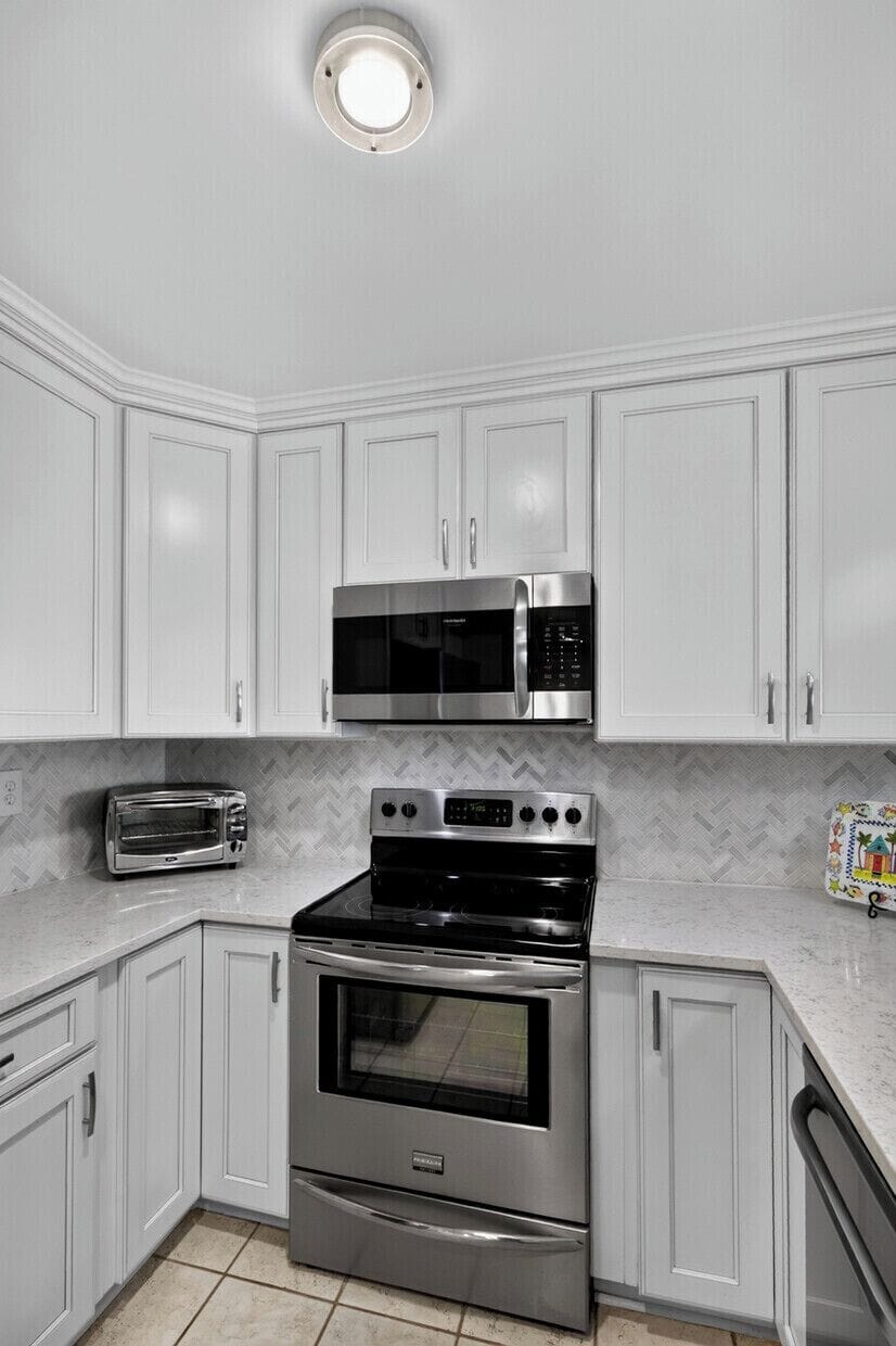 Cook your favorite meals in this bright, modern kitchen featuring stainless steel appliances, ample cabinet storage, and elegant herringbone tile backsplash.
