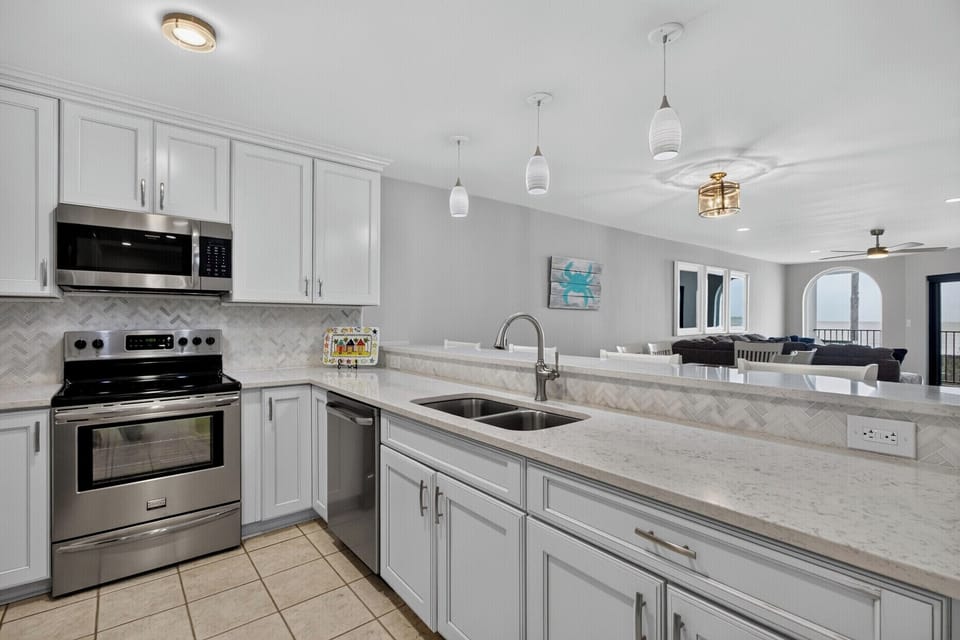 Cook your favorite meals in this bright, fully-equipped kitchen featuring modern appliances, ample counter space, and an open view to the living area for easy entertaining.