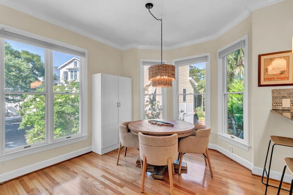 Gather around the table in this sun-filled dining space, where large windows frame leafy neighborhood views. Warm wood floors and soft natural light create the perfect setting for your morning coffee or evening meals together.