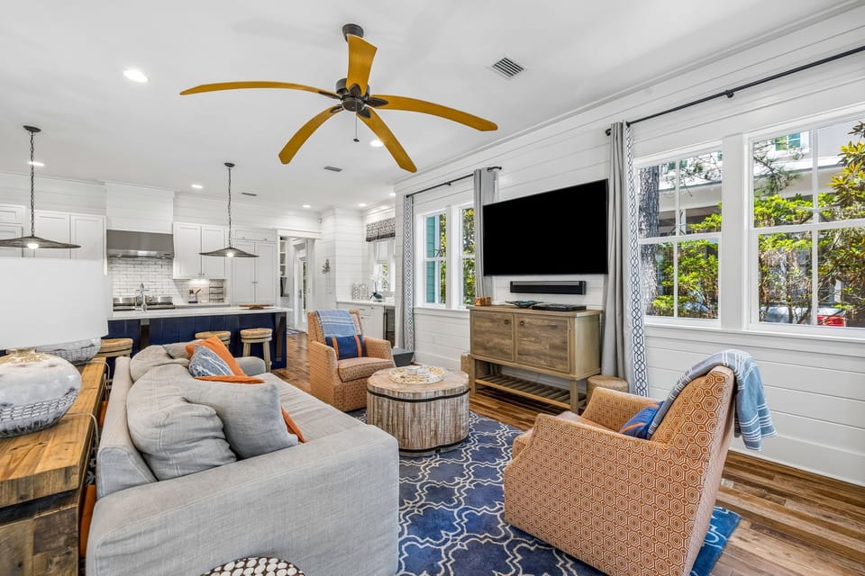 Relax in your bright, open-concept living space with comfortable seating, coastal decor, and large windows that invite natural light and garden views. The seamless flow into the full kitchen makes this your perfect gathering spot.