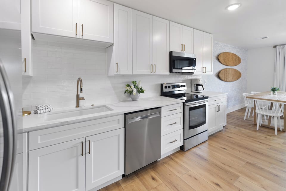 Bright, modern kitchen with white cabinetry and stainless appliances opens to your dining area, perfect for preparing meals and gathering with loved ones.