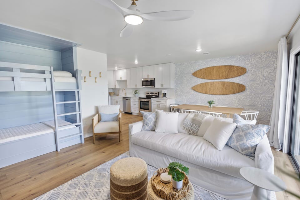Kick back in your serene coastal retreat, where a plush white sofa and cozy bunk nook blend comfort with breezy, beachy style.