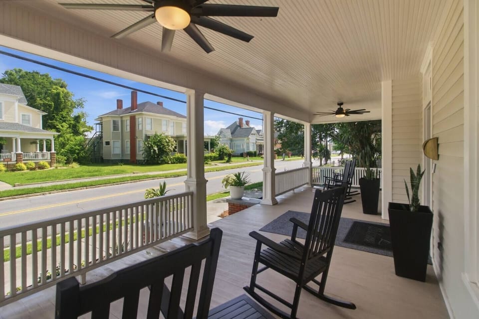 Grand Veranda Views: Settle into our deep-porch lifestyle featuring premium black acacia rocking chairs, custom outdoor runners, and a historic 1904 view of the Fairview District.