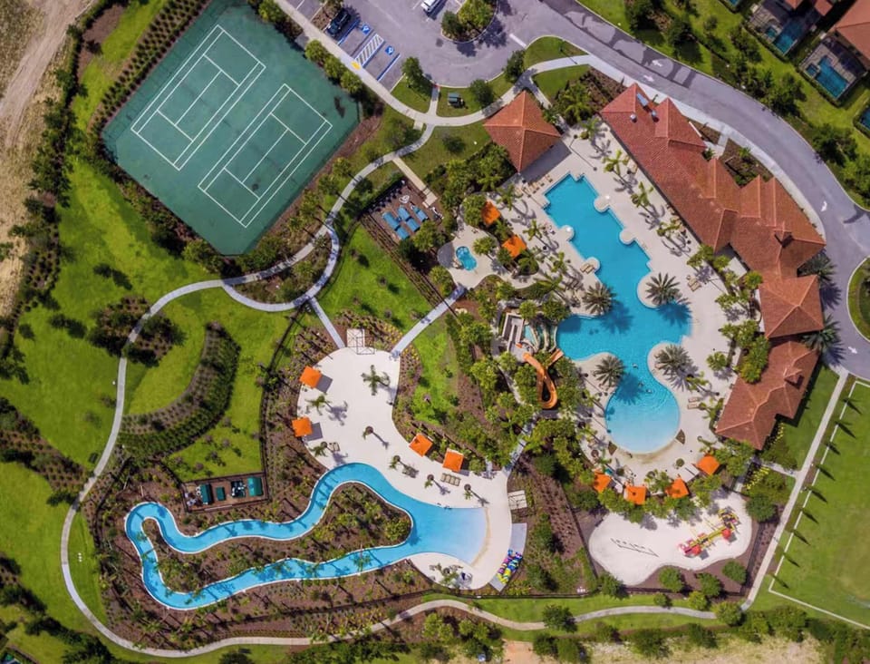 Aerial view of the resort's tennis courts, pools, and lazy river surrounded by lush landscaping.