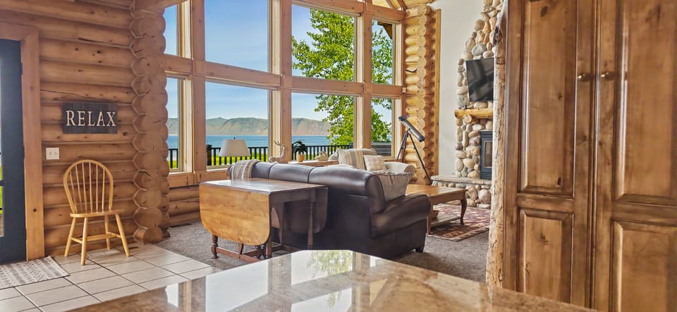 Cozy log cabin living room with lake views and a stunning stone fireplace