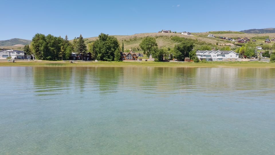 Tranquil waterfront views with clear water, trees, and rolling hills