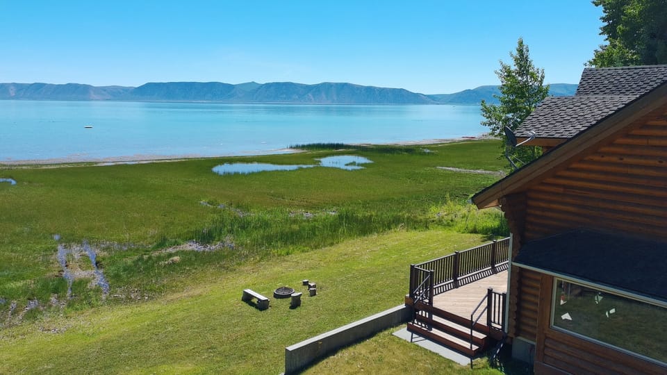 Scenic lakeside cabin with mountain views, deck, yard, and fire pit