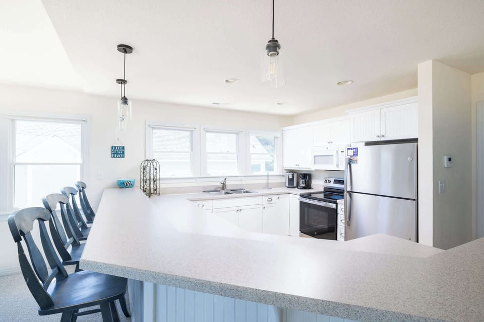 Fully Equipped Kitchen with Refrigerator, Range and Oven, Microwave, Dishwasher, Dual Coffee Makers, Ample Counter Space, and a Breakfast Bar with Seating, Perfect for Preparing Meals and Gathering with Family and Friends