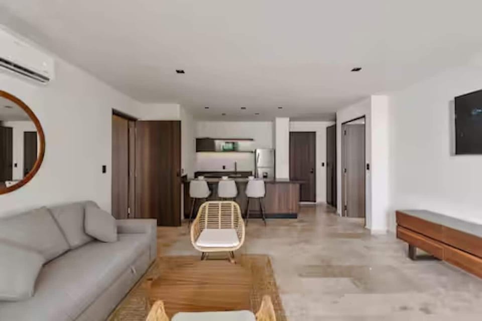 Bright living room with sofa, lounge chairs, and open kitchen views.