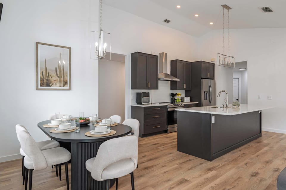Modern kitchen and dining area with dark cabinetry and a spacious island.
